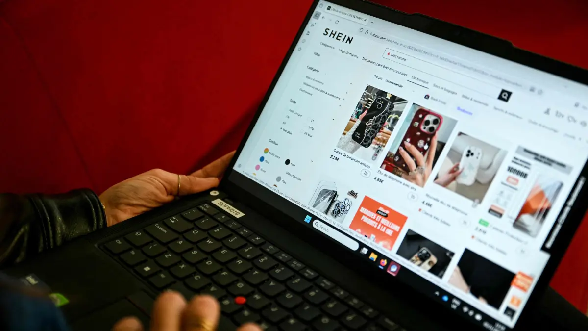 An internet user checks the Asian e-commerce giant Shein website page on a laptop in Paris on November 5, 2025. Shein announced to AFP on November 5, 2025 that it is suspending its "marketplace" in France, meaning the products offered online by third-party sellers, after the scandal linked to the sale of sex dolls resembling little girls. (Photo by Julie SEBADELHA / AFP)
