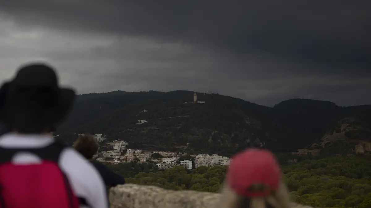 Menschen schauen in die Wolken am Castell de Bellver. Auch die Balearen erwarten Unwetter auf den beliebten Touristeninseln Mallorca und Menorca. Bisher gilt dort die zweithöchste Warnstufe Orange. +++ dpa-Bildfunk +++
