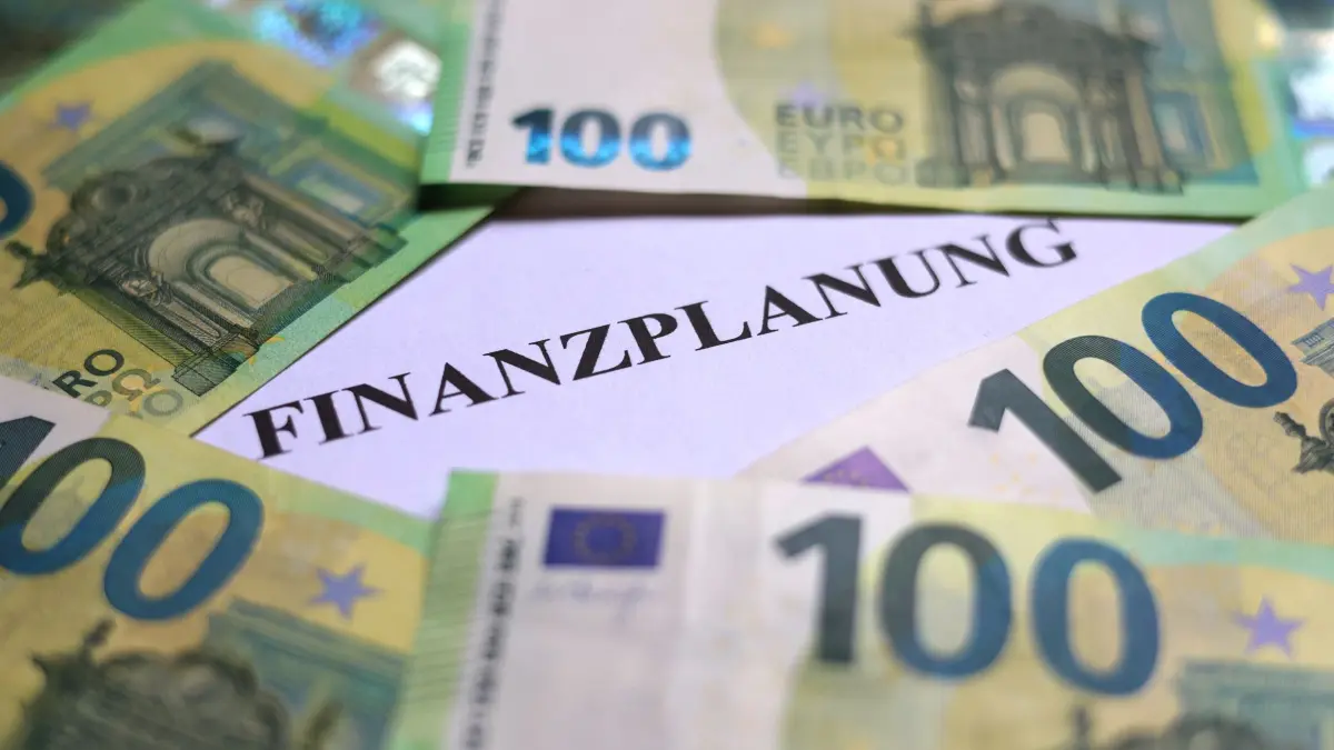 Symbolbild Geld: ILLUSTRATION - 03.06.2025, Bayern, Augsburg: 100-Euro-Banknoten liegen um das Wort «Finanzplanung». (zu dpa: «Ortsgemeinden warnen vor finanziellem Kollaps») Foto: Karl-Josef Hildenbrand/dpa +++ dpa-Bildfunk +++