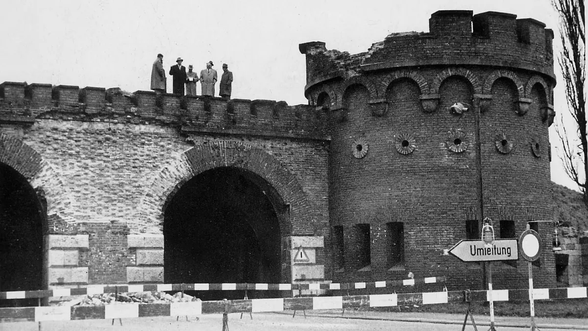 Ulm, Blaubeurer Tor, Zerfall: Im Jahr 1957 zeigte das Tor unerklärliche Zerfallserscheinungen. Obendrauf stehen Mitglieder des Gemeinderates, um den Ursachen auf den Grund zu gehen. Im Vordergrund Absperrungen und ein Umleitungsschild.