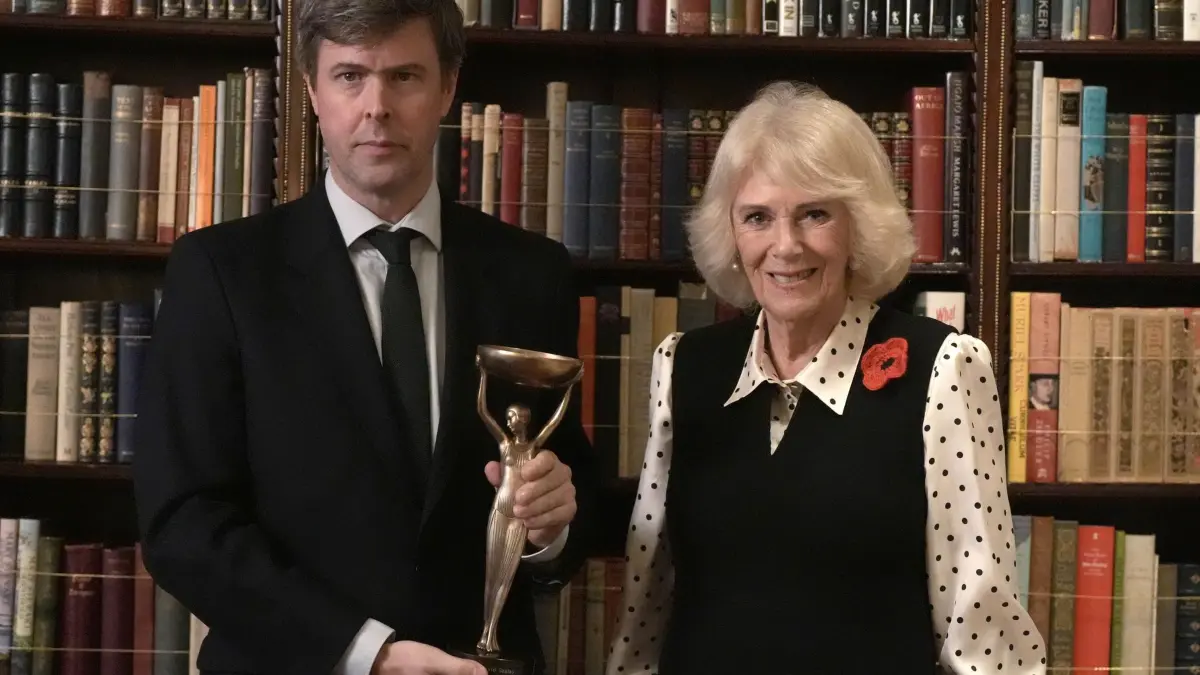 Booker-Preis 2025: 11.11.2025, Großbritannien, London: Königin Camilla mit dem Gewinner des Booker-Preises 2025, David Szalay, während eines Empfangs für die in die engere Wahl gekommenen Autoren, Jurymitglieder und Unterstützer anlässlich der Verleihung des Booker-Preises 2025 und des neu angekündigten Booker-Preises für Kinder im Clarence House in London. Der ngarisch-britische Schriftsteller David Szalay erhielt den Booker Prize 2025 für sein Buch "Flesh". Foto: Stefan Rousseau/PA Wire/dpa +++ dpa-Bildfunk +++
