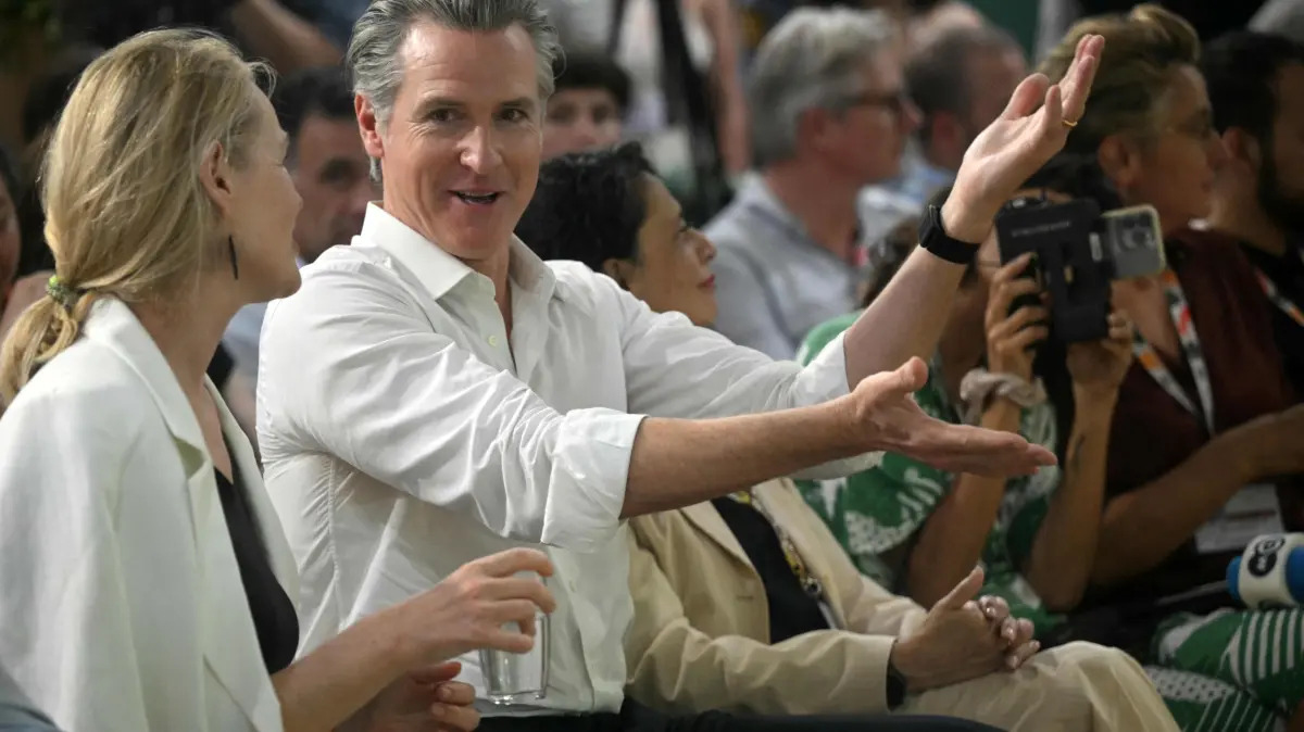The Governor of California Gavin Newsom speaks with a woman during the COP30 UN Climate Change Conference, in Belem, Para State, Brazil, on November 11, 2025. President Donald Trump's administration may have steered clear of this year's UN climate summit in the Brazilian Amazon, but the conference's second day is nonetheless set to be dominated by the governors of California and New Mexico. (Photo by Mauro PIMENTEL / AFP)