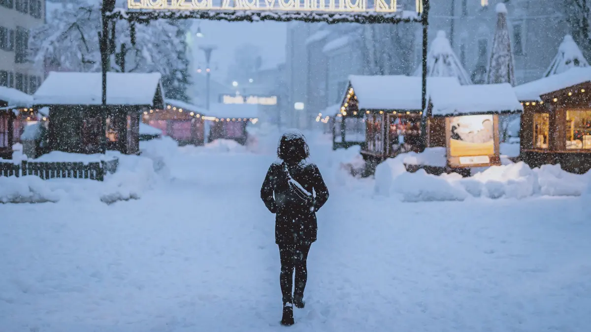 Eine Fußgängerin geht über den verschneiten Lienzer Adventmarkt. Der Winter macht sich in Teilen Österreichs mit enormen Schnee- und Regenmengen bemerkbar. Die anhaltend starken Schneefälle sowie Sturm auf den Bergen sorgten in Osttirol für erhebliche Behinderungen und hohe Lawinengefahr. +++ dpa-Bildfunk +++