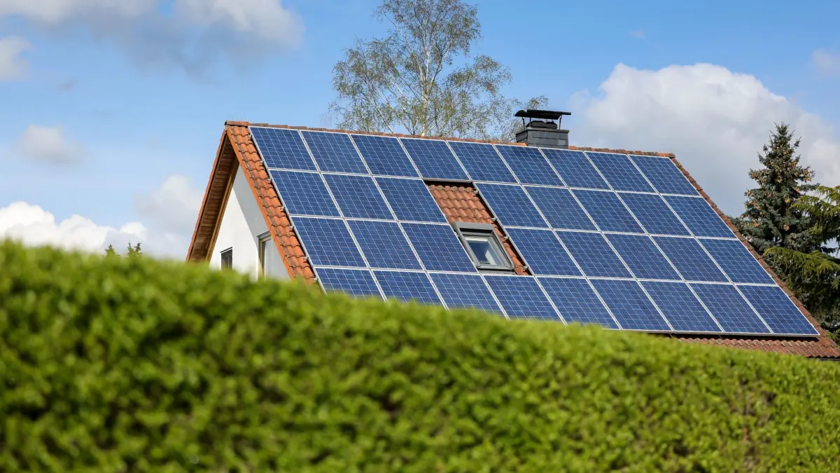 Photovoltaikanlage auf Hausdach: ARCHIV - 03.05.2021, Sachsen, Leipzig: Ein Einfamilienhaus mit Solarpaneelen auf dem Hausdach steht hinter einer grünen Hecke. (zu dpa: «Bundestag erleichtert «Energy Sharing»») Foto: Jan Woitas/dpa-Zentralbild/dpa +++ dpa-Bildfunk +++