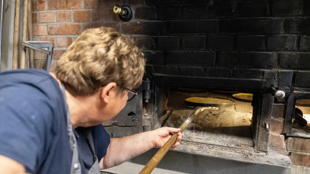 Backtag in Dettingen: Cornelia Randecker, Verantwortliche im oberen Backhaus, schiebt Rahmkuchen in den historischen Ofen.