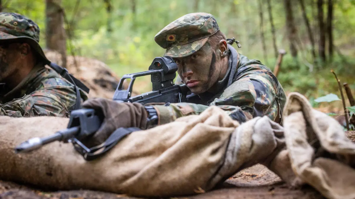 Wehrdienst-Einigung: Es bleibt zunaechst bei Freiwilligkeit: Soldaten in Camouflage an der Waffe im Schuetzengraben waehrend der Basisausbildung auf dem Truppenuebungsplatz der Panzerdivision in Munster (Foto vom 16.09.2025). Die Koalition von Union und SPD hat sich auf die Ausgestaltung des neuen Wehrdienstes geeinigt. Wie die Fraktionsvorsitzenden Jens Spahn (CDU) und Matthias Miersch (SPD) am Donnerstag in Berlin mitteilten, soll es zunaechst bei einem Dienst auf freiwilliger Basis bleiben. Spahn zufolge soll aber ein "verbindlicher Aufwuchspfad" gesetzlich festgehalten werden mit einer halbjaehrlichen Berichtspflicht an den Bundestag. Wird der nicht eingehalten, kann es Spahn und Miersch zufolge zu einer "Bedarfswehrpflicht" kommen, ueber die zunaechst aber erneut der Bundestag abstimmen muesste. Zudem soll der allgemeine Freiwilligendienst ausgebaut werden. (Siehe epd-Meldung vom 13.11.2025)