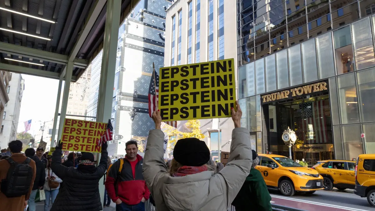 Proteste vor Trump Tower: 16.11.2025, USA, New York: Friedliche Anti-Trump-Demonstranten skandieren mit Schildern und Transparenten vor dem Trump Tower, während Autos, Touristen und Einkäufer auf der Fifth Ave. vorbeifahren. Die Demonstranten von "Rise and Resist" halten amerikanische Flaggen und Schilder mit der Aufschrift "EPSTEIN! EPSTEIN! EPSTEIN! EPSTEIN!", während sie mit den Slogans "No Troops In Our Cities We Need Food and Healthcare Not Ballrooms" demonstrieren. Foto: Gina M Randazzo/ZUMA Press Wire/dpa +++ dpa-Bildfunk +++