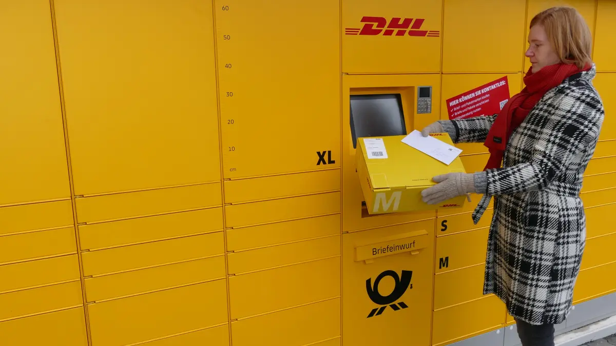 Frau nimmt Paket aus Packautomaten
