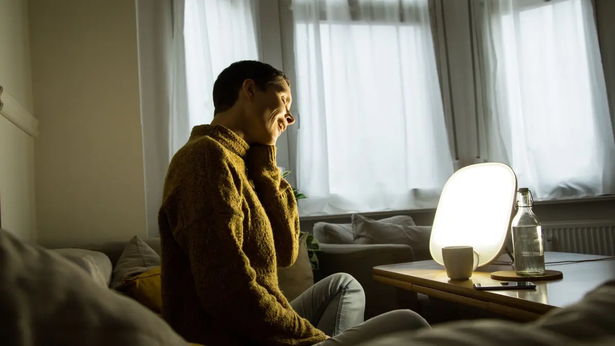 Frau sitzt vor einer Tageslichtlampe