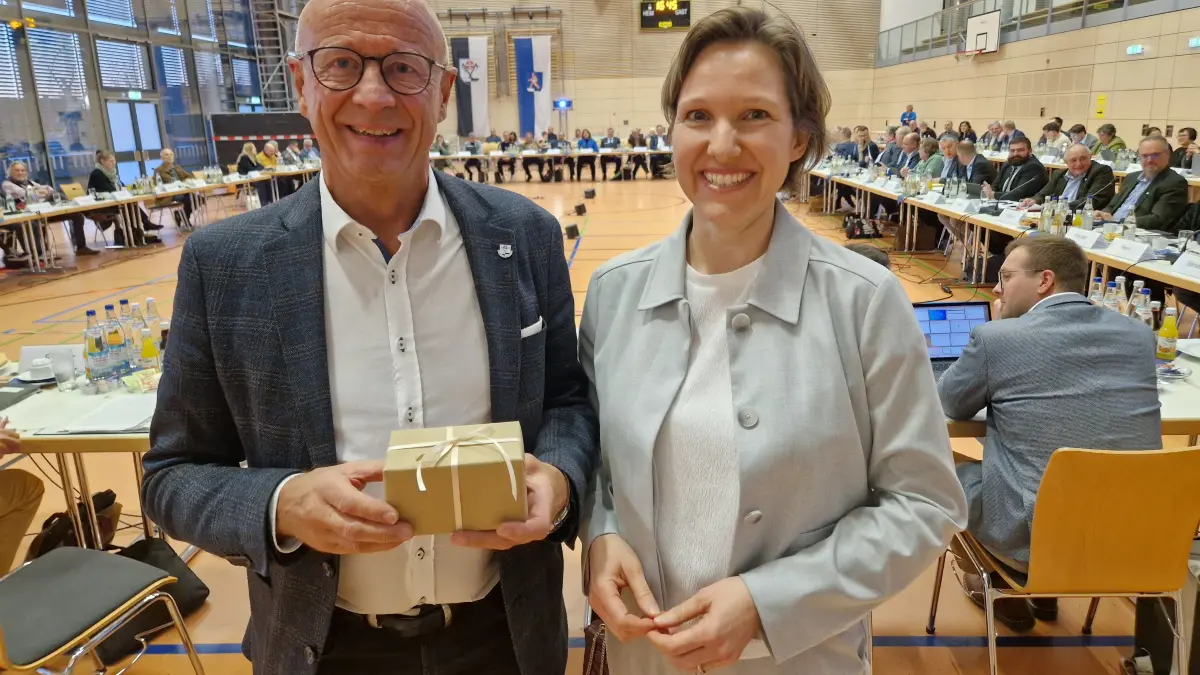 Isabell Rathgeb (CDU) überreicht nach ihrer Haushaltsrede ein Geschenk an Landrat Gerhard Bauer. In dem Päckchen befindet sich Tee, der dem Landrat „Kraft und Mut“ geben soll.