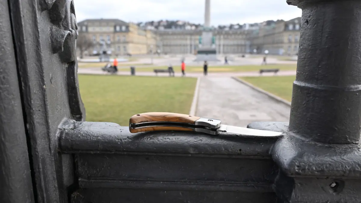 Waffenverbotszone: ILLUSTRATION - 23.01.2025, Baden-Württemberg, Stuttgart: Ein Messer liegt in der Innenstadt griffbereit (gestellte Szene), im Hintergrund der Schlossplatz. Messer und andere Waffen bleiben in Stuttgarts City verboten. (zu dpa: «Das spricht für und das gegen das Messerverbot im Nahverkehr») Foto: Bernd Weißbrod/dpa +++ dpa-Bildfunk +++