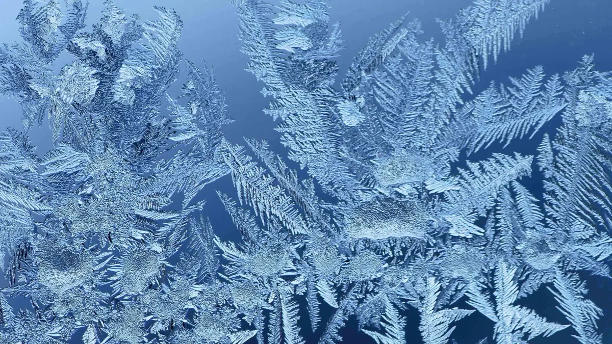 Eisblumen sind nach einer eisig kalten Nacht an einem Fenster zu sehen.