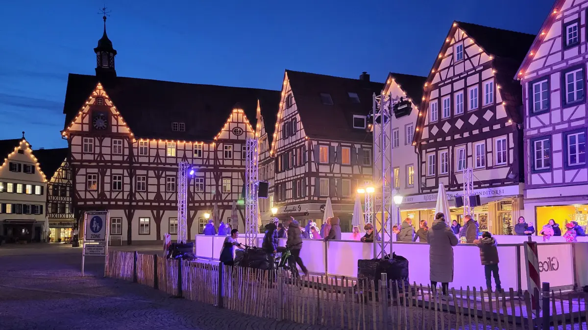 Inmitten der Fachwerkhauskulisse steht auf dem Bad Uracher Marktplatz eine synthetische Schlittschuhbahn. Die Belebung der Innnenstadt bringt die Attraktion durch Licht und Musik.