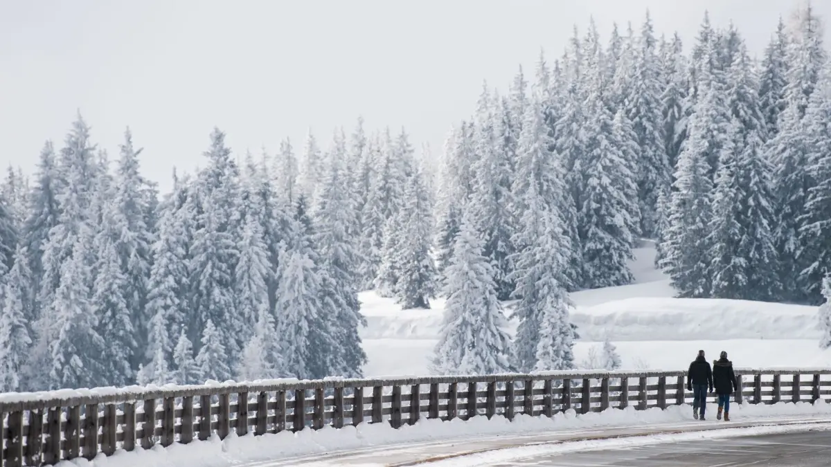 Wetter in Bayern: ARCHIV - 25.02.2018, Bayern, Eck: Ein Paar geht an dem Rossfeld Panoramaweg an der deutsch-österreichischen Grenze am verschneiten Geländer entlang. (zu dpa: «Unfall beim Driften auf schneeglatter Panoramastraße») Foto: Lino Mirgeler/dpa +++ dpa-Bildfunk +++