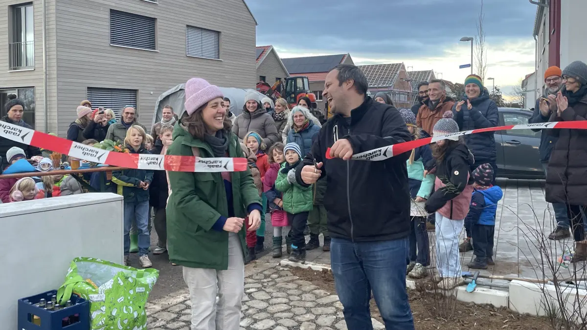 Projektplanerin Paula Dondon und Ortsvorsteher Sascha Fleck eröffnen die neue Spielfläche in Bühl. Zahlreiche Kinder und ihre Eltern warten darauf, endlich den Spielplatz nutzen zu können.