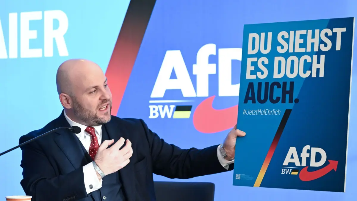 23.11.2025, Baden-Württemberg, Hechingen: Markus Frohnmaier, der Spitzenkandidat der AfD für die Landtagswahl in Baden-Württemberg 2026 zeigt beim Landesparteitag der AfD bei einer Pressekonferenz ein Wahlplakat mit der Aufschrift «Du siehst es doch auch». Foto: Bernd Weißbrod/dpa - ACHTUNG: Verwendung nur im vollen Format +++ dpa-Bildfunk +++