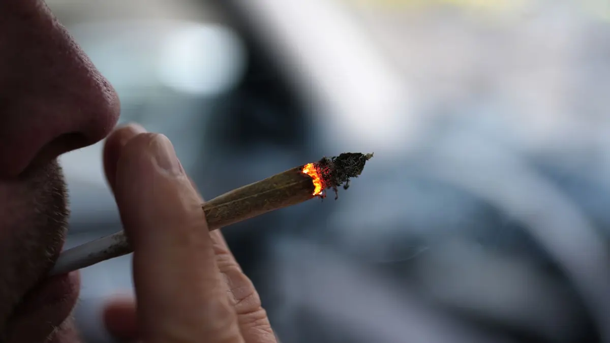 Cannabis: ARCHIV - 05.01.2025, Hamburg: ILLUSTRATION - Ein Mann raucht während der Autofahrt am Steuer einen Joint. (zu dpa: «Jugendliche werden kaum noch für Cannabis-Konsum bestraft») Foto: Marcus Brandt/dpa +++ dpa-Bildfunk +++