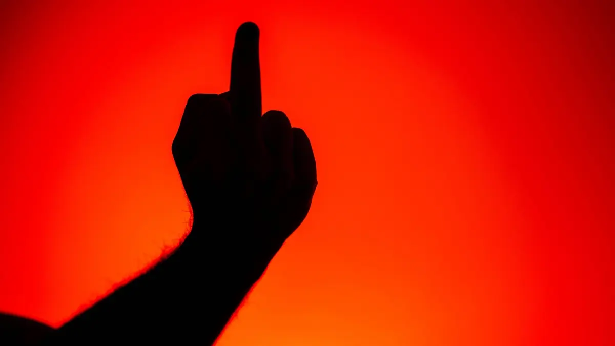 Eine Person zeigt den Mittelfinger: ILLUSTRATION - Weint die Schichtmutter oder nicht? Ein Gericht entschied: Vulgäre Kritik ist nicht automatisch ein Kündigungsgrund. Foto: Sina Schuldt/dpa/dpa-mag - Honorarfrei nur für Bezieher des Dienstes dpa-Magazin +++ dpa-Magazin +++