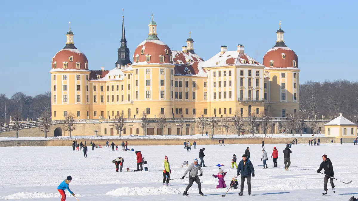 Zahlreiche Menschen sind auf dem zugefrorenen Schlossteich vor dem Schloss Moritzburg, dem einstigen Jagdschloss der Wettiner, unterwegs. +++ dpa-Bildfunk +++