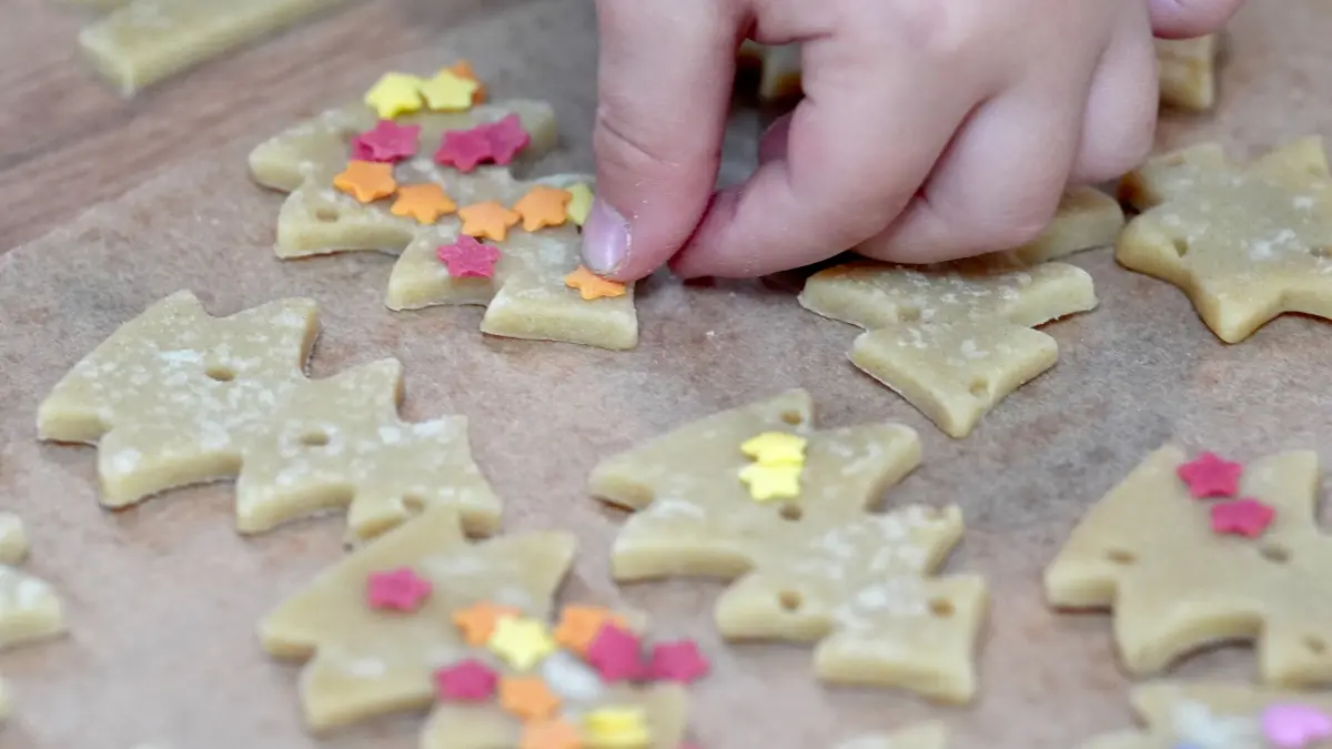 Ein Kind belegt die ausgestochenen Kekse mit bunten Streuseln während der Eröffnung der Hamburger Märchenschiffe am Anleger Jungfernstieg. Kinder können bis zum 23. Dezember 2025 an Bord der Schiffe Kekse backen, Theatervorstellungen und Märchen besuchen oder sich schminken lassen. +++ dpa-Bildfunk +++