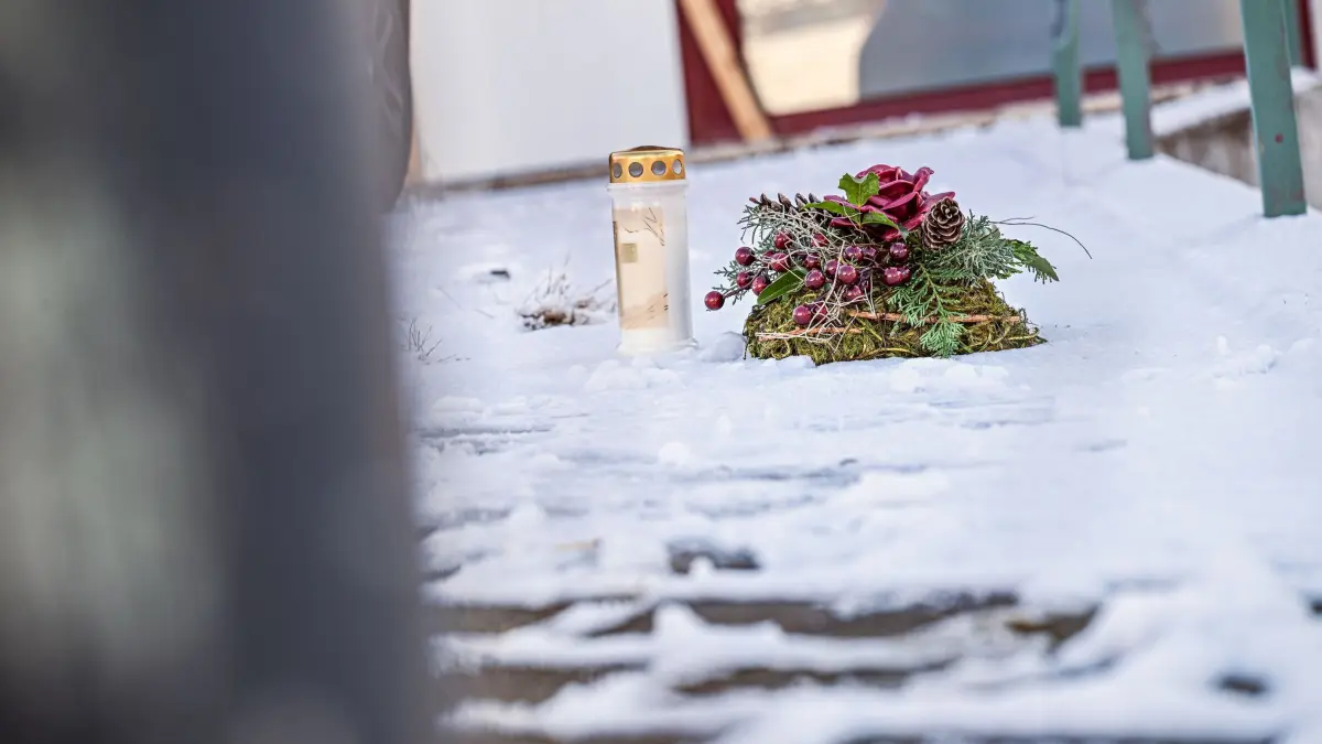 Weitere Ermittlungen nach Gewalttat mit fünf Toten: 27.11.2025, Baden-Württemberg, Sankt Johann: Eine Kerze steht neben einem Kranz an einem Tatort vor einem Firmengelände im Landkreis Reutlingen. Nach einer Gewalttat mit fünf Toten an drei Tatorten im Landkreis Reutlingen sind nach Polizeiangaben zahlreiche Hinweise bei den Ermittlern eingegangen. Bei der Durchsuchung eines Wohnhauses in Pfullingen hatten Spezialeinsatzkräfte am Dienstagabend die Leichen eines 63-Jährigen und seiner 57 Jahre alten Ehefrau gefunden. Unklar ist weiterhin das Motiv des 63 Jahre alten Mannes, der seine Ehefrau, seine Schwester, seine beiden Söhne und anschließend sich selbst getötet haben soll. Foto: Jason Tschepljakow/dpa +++ dpa-Bildfunk +++