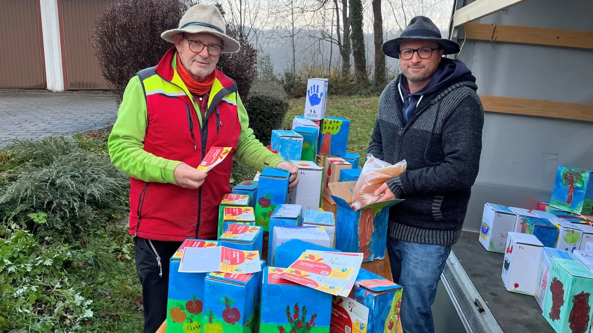 Karl Götz (links) und Stefan Öhlschläger befüllen die farbenfrohen Kartons mit den Apfelsaft-Beuteln und versehen sie mit Aufklebern – ehrenamtlich, versteht sich.