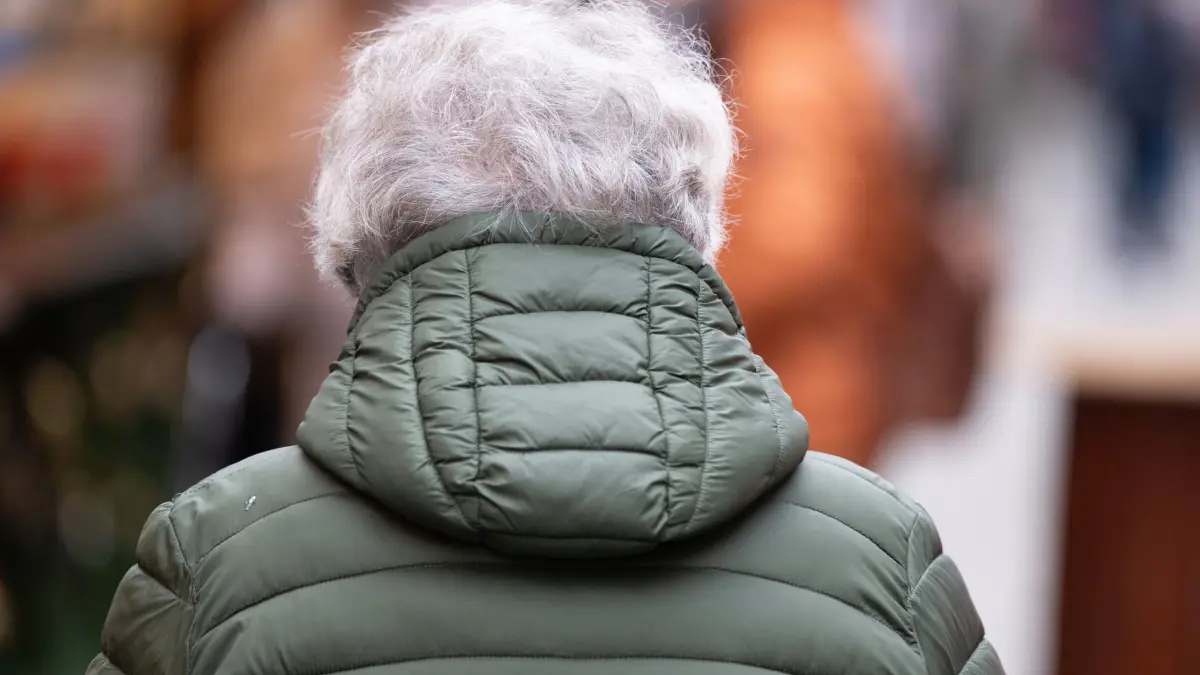 Rente: 27.11.2025, Sachsen, Dresden: Eine ältere Person mit grauen Haaren geht über einen Weihnachtsmarkt. Die Spitzen von Union und SPD wollen heute Abend im Koalitionsausschusses unter anderem nach einer Lösung im Streit über das Rentenpaket suchen. Foto: Sebastian Kahnert/dpa +++ dpa-Bildfunk +++