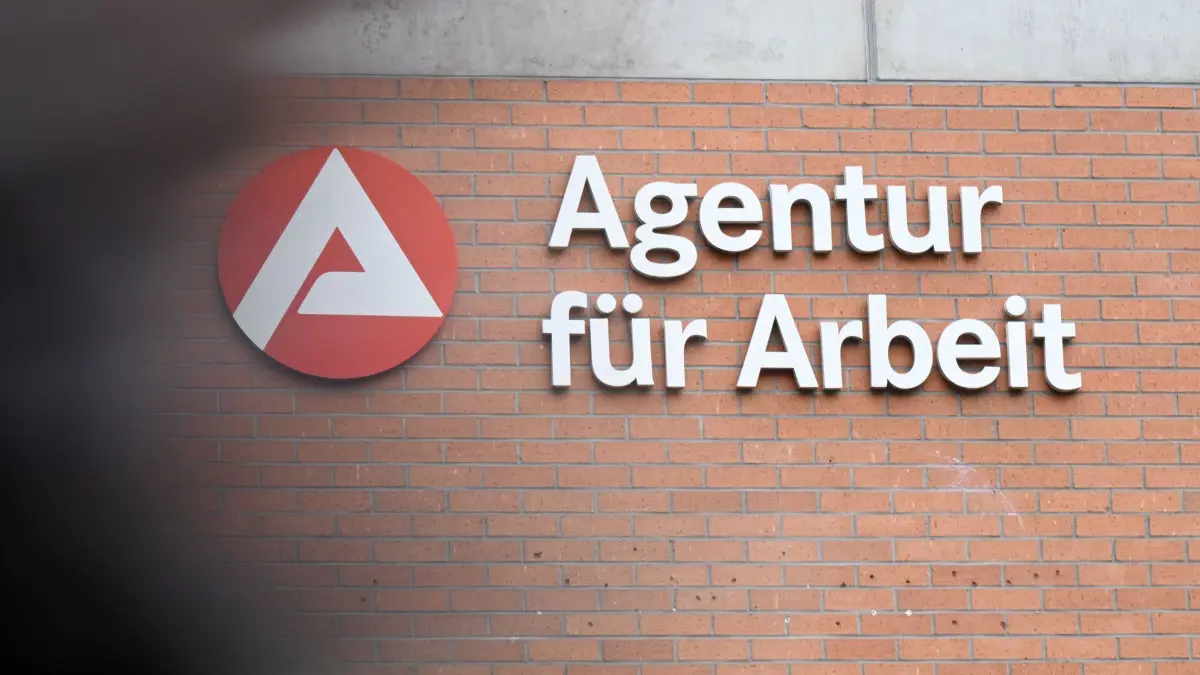 Arbeitsmarkt - Bundesagentur für Arbeit: PRODUKTION - 27.11.2025, Baden-Württemberg, Eßlingen: An einem Gebäude der Bundesagentur für Arbeit ist das Logo der Arbeitsagentur angebracht. Davor läuft ein Mensch (Wischeffekt durch Langzeitbelichtung). Die Bundesagentur für Arbeit veröffentlicht am 28.11.2025 ihren Arbeitsmarktbericht für Monat November 2025. Foto: Bernd Weißbrod/dpa +++ dpa-Bildfunk +++
