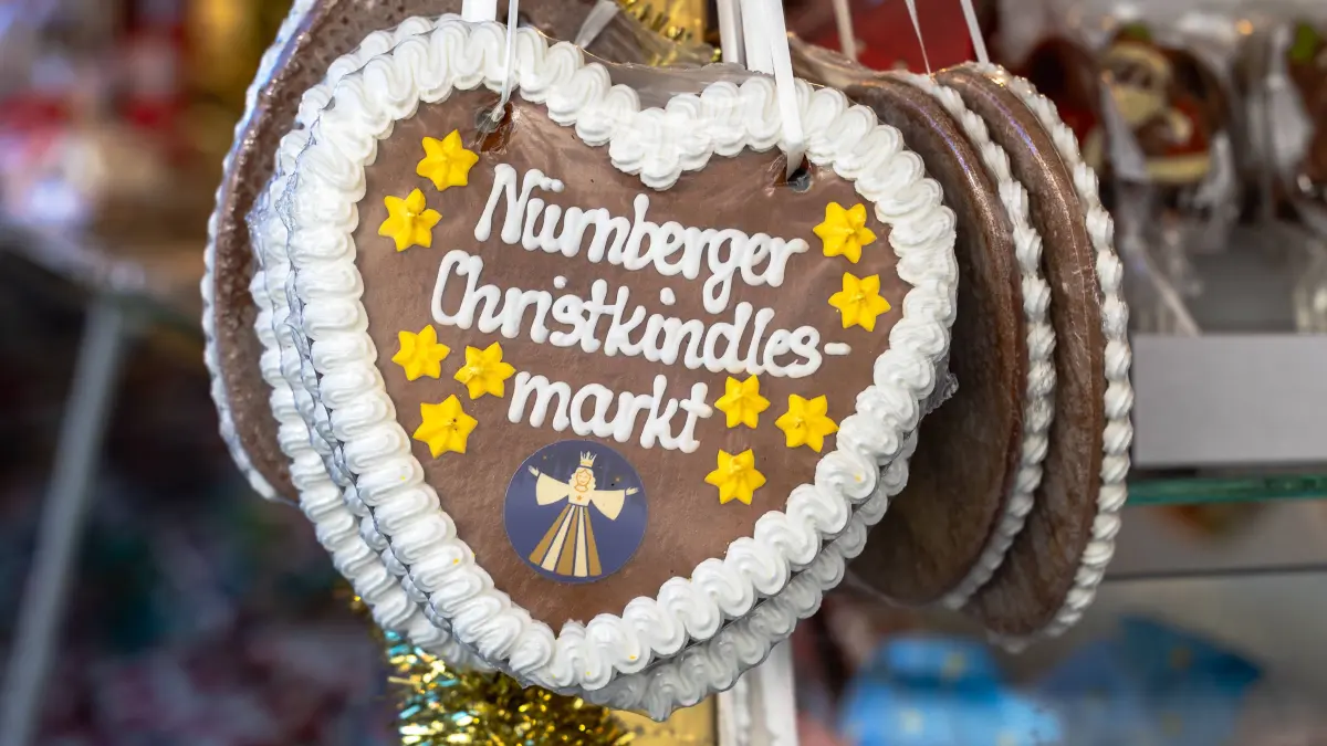 Presserundgang auf dem Christkindlesmarkt 2025, Nürnberg, 01.12.2025: Presserundgang auf dem Christkindlesmarkt 2025, Nürnberg, 01.12.2025 Nahaufnahme eines Lebkuchenherzens mit weißer Zuckerschrift und gelben Ziersternen, ausgestellt an einem Verkaufsstand auf einem Weihnachtsmarkt. Das Herz trägt die Aufschrift Nürnberger Christkindlesmarkt und ein rundes Logo mit der stilisierten Figur des Christkinds. Nürnberg Bayern Deutschland *** Press tour at the Christkindlesmarkt 2025, Nuremberg, 01 12 2025 Close-up of a gingerbread heart with white sugar lettering and yellow decorative stars, displayed at a stall at a Christmas market The heart bears the inscription Nuremberg Christkindlesmarkt and a round logo with the stylized figure of the Christ Child Nuremberg Bavaria Germany 20251201-6V2A2844-M4000