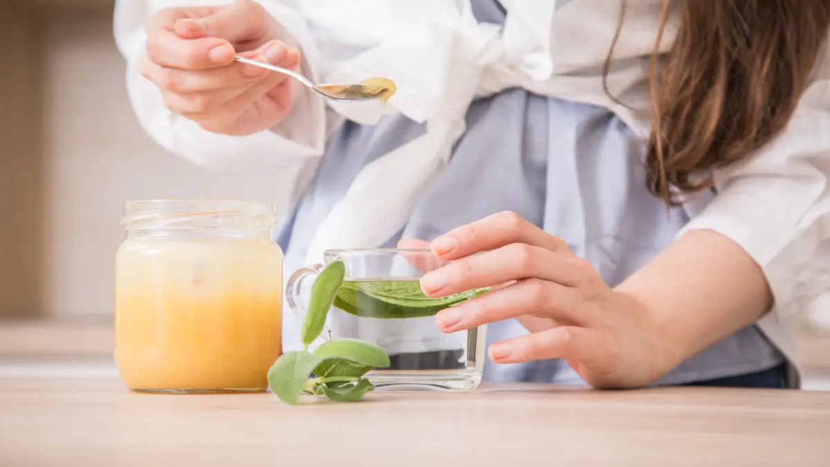 Eine Frau bereitet frischen Salbeitee mit Honig zu: ILLUSTRATION - Frischer Tee mit lecker Honig: Beruhigt den Hals und schmeckt auch gut. (zu dpa: «Husten in den Griff bekommen: Lungenarzt gibt Tipps») Foto: Christin Klose/dpa Themendienst/dpa-tmn - Honorarfrei nur für Bezieher des dpa-Themendienstes +++ dpa-Themendienst +++