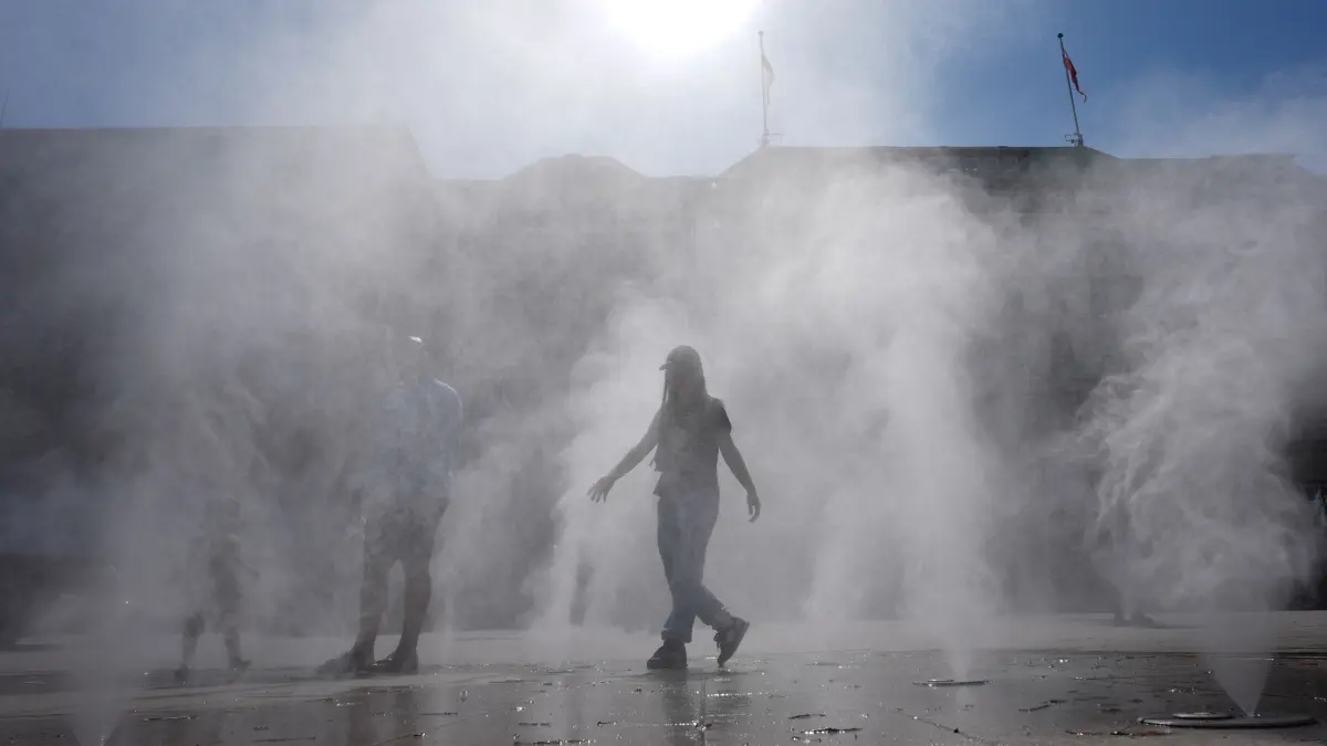 Jahreswechsel 2025: 13.08.2025, Hamburg: Passanten gehen durch einen Sprühnebel eines Wasserzerstäubers am Jungfernstieg in der Innenstadt. Foto: Marcus Brandt/dpa +++ dpa-Bildfunk +++