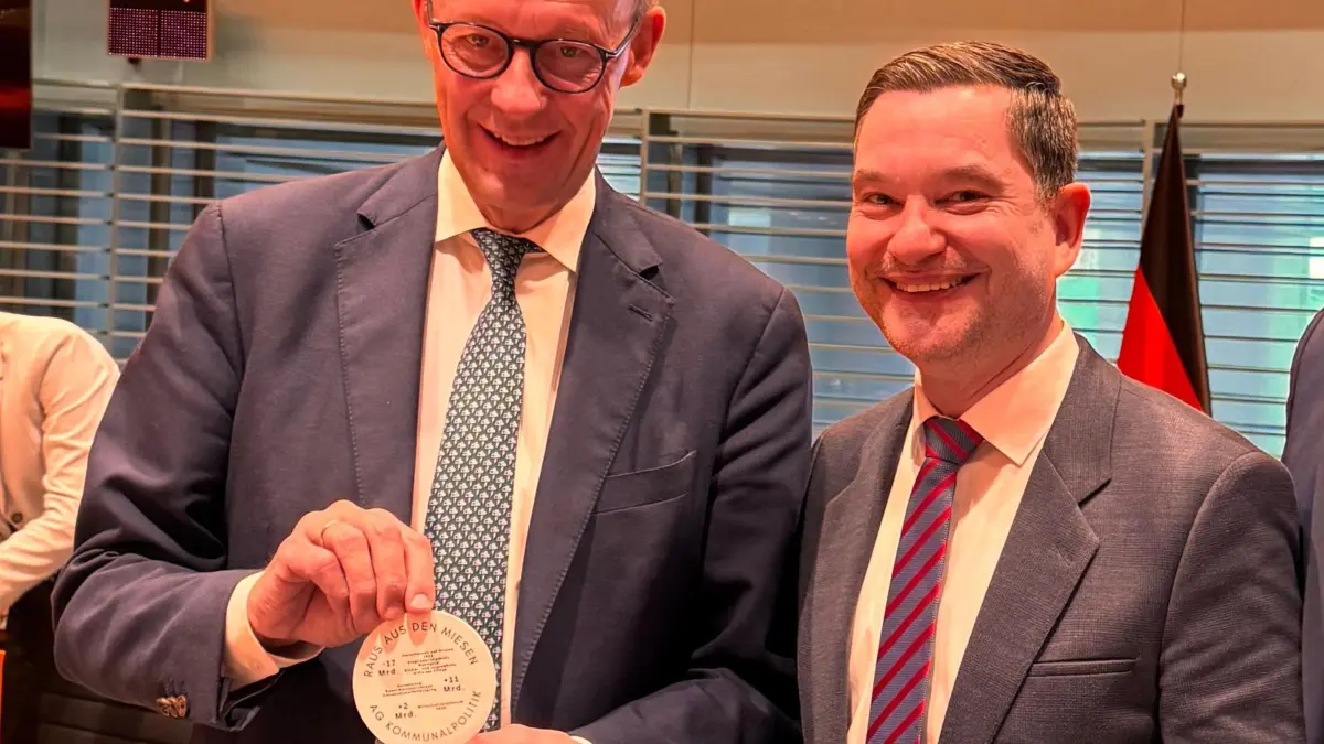 Bundeskanzler Friedrich Merz (links) erhält von Klaus Mack neuen Bierdeckel - nicht mit der vereinfachten Steuererklärung, sondern mit der klar umrissenen Darstellung der finanziellen Lage der Kommunen.
