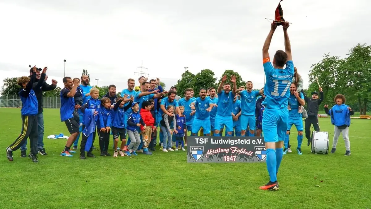 Dennis Schlander, Kapitän der TSF Ludwigsfeld, reckt die Meister-Trophäe 2025 in die Höhe.