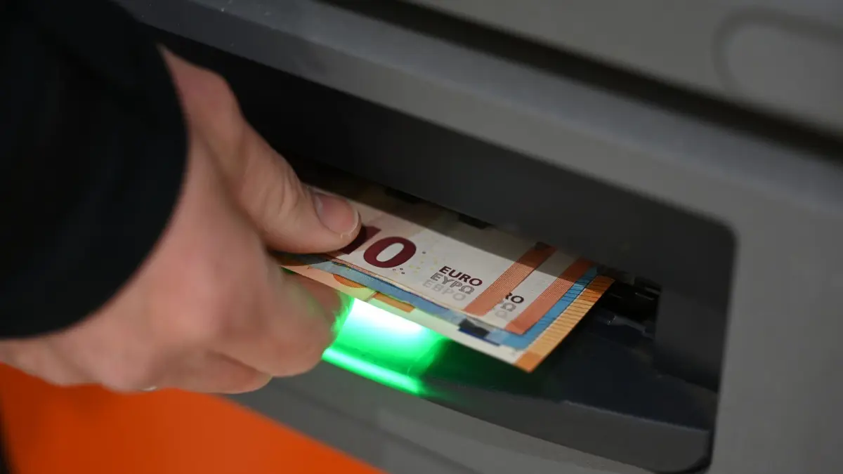 Inflationsrate: PRODUKTION - 12.03.2025, Sachsen, Leipzig: Ein Mann zieht Geldscheine aus dem Ausgabefach eines Geldautomaten. (zu dpa: «Unbekannte erbeuten sechsstellige Summe aus Bankautomat») Foto: Elisa Schu/dpa +++ dpa-Bildfunk +++
