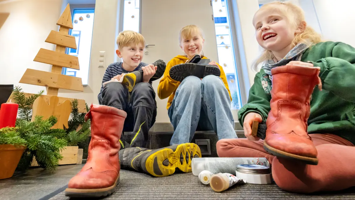 Vorbereitungen auf den Nikolaustag - Nikolaus kommt - Kinder putzen ihre Stiefel - Kilian (9), Antonia (6) und Friederike " Fritzi" Weigand (12) sitzen im Flur in Steinbach und freuen sich, dass sie Geschenke bekommen