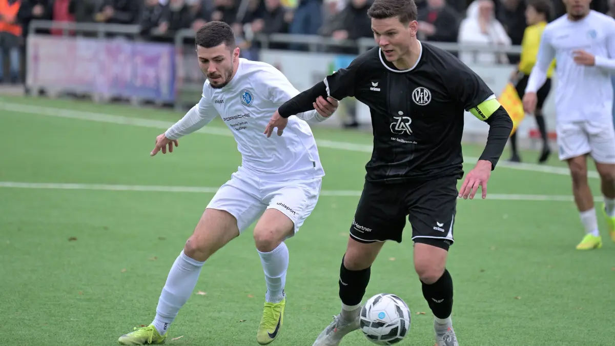 Fussball VL | Young Boys Reutlingen vs. VfR Heilbronn: Fussball VL | Young Boys Reutlingen (weiss) vs. VfR Heilbronn (schwarz) // 2025-12-06 // Foto: Joachim Baur // #11 Ante Galic (Young Boys Reutlingen) / #18 Anthony Syhre (VfR Heilbronn)