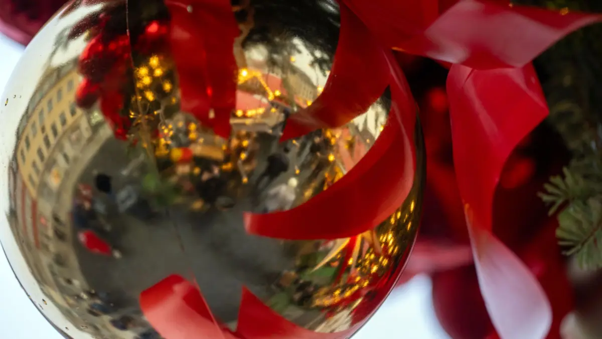 Wetter in Bayern: 07.12.2025, Bayern, Coburg: Regentropfen liegen auf einer Christbaumkugel, in der sich ein Weihnachtsmarkt spiegelt. Foto: Pia Bayer/dpa +++ dpa-Bildfunk +++