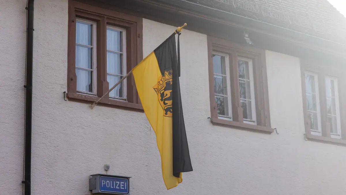 Polizist kommt bei Unfall mit Streifenwagen um: 09.12.2025, Baden-Württemberg, Titisee-Neustadt: Die Landesfahne von Baden-Württemberg hängt gemeinsam mit einem Trauerflor am Polizeirevier in Titisee-Neustadt. Ein 37-jähriger Polizist war am Sonntagabend mit einem weiteren Beamten auf der Landstraße zwischen den Ortsteilen Titisee und Neustadt unterwegs gewesen, wie die Polizei mitteilte. Aus ungeklärter Ursache kam der Streifenwagen demnach in einer Kurve von der Straße ab, überschlug sich und prallte gegen einen Baum. Der 37-jährige Fahrer erlag noch am Unfallort seinen Verletzungen. Sein 25-jähriger Beifahrer und Kollege wurde schwer verletzt in ein Krankenhaus gebracht. Foto: Philipp von Ditfurth/dpa +++ dpa-Bildfunk +++