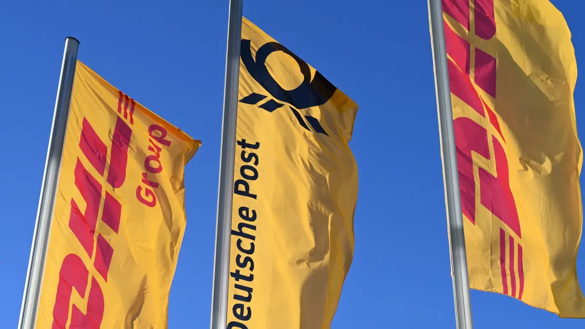Post-Fahne mit Posthorn: ARCHIV - 13.01.2025, Nordrhein-Westfalen, Bonn: Fahnen des Logistikkonzerns DHL und seiner Brieftochter Deutsche Post (M) wehen vor der Konzernzentrale an Masten. Bei der Bundesnetzagentur sind so viele Beschwerden über Postdienstleistungen eingegangen wie noch nie, die allermeisten davon betrafen den Marktführer Deutsche Post/DHL. (zu dpa: «Rekord bei Beschwerden über Post - aber Lage bessert sich») Foto: Wolf von Dewitz/dpa +++ dpa-Bildfunk +++
