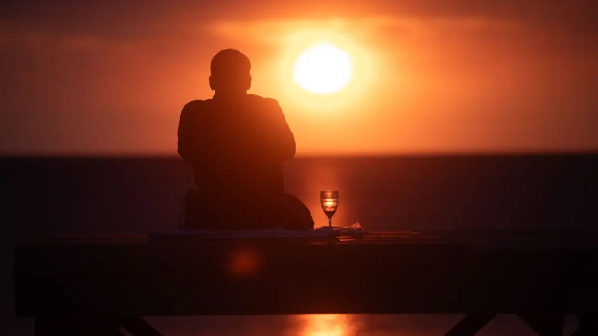Wetter auf Mallorca: 13.12.2025, Spanien, Palma: Ein Mann beobachtet den Sonnenuntergang am Meer am Strand von Arenal auf Mallorca. Foto: Clara Margais/dpa +++ dpa-Bildfunk +++