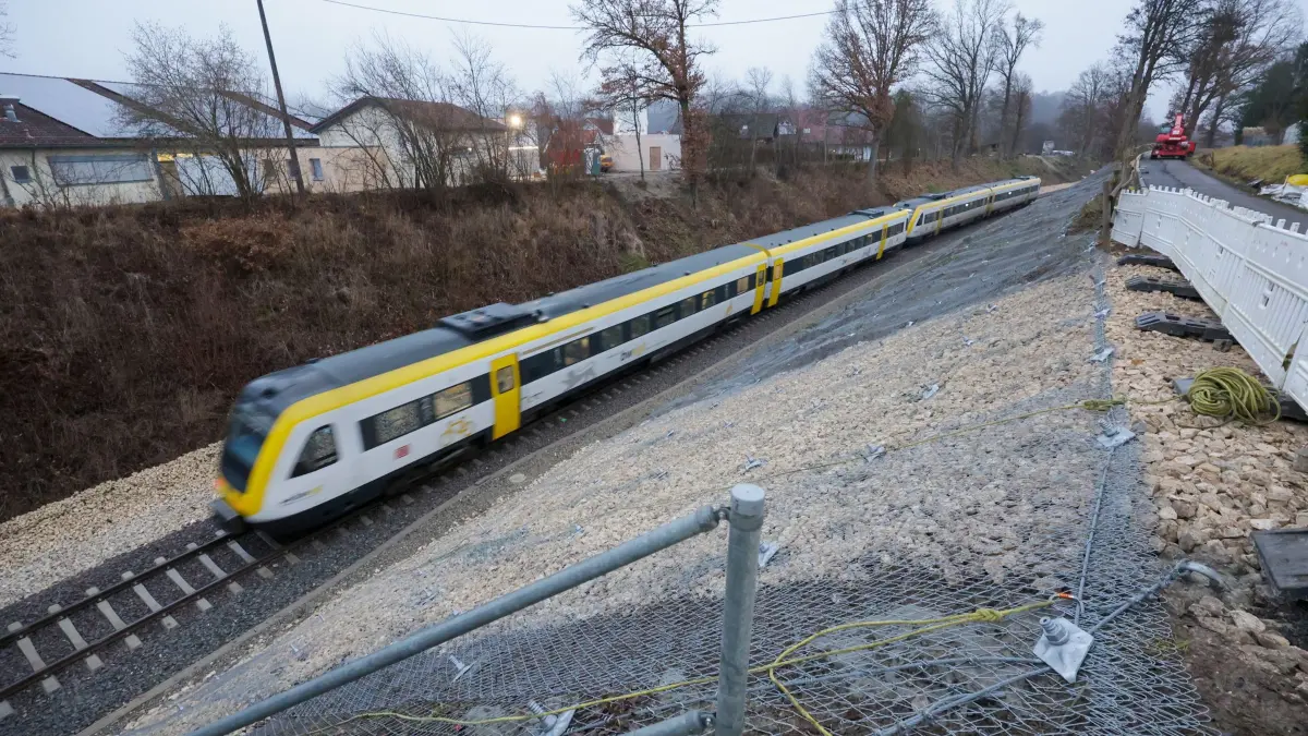 Bahnstrecke nach Zugunglück in Riedlingen wieder befahrbar: 14.12.2025, Baden-Württemberg, Riedlingen: Der Regionalzug RE55 passiert die Unfallstelle zwischen den Ortsteilen Zwiefaltendorf und Zell. Mehr als vier Monate nach dem schweren Zugunglück mit drei Toten und Dutzenden Verletzten fahren auf der betroffenen Bahnstrecke wieder Züge. (zu dpa: «Bahnstrecke nach Zugunglück in Riedlingen wieder frei») Foto: Thomas Warnack/dpa +++ dpa-Bildfunk +++