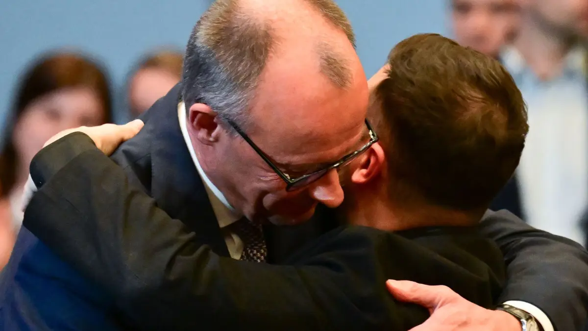 Ukraine-Beratungen in Berlin: 15.12.2025, Berlin: Wolodymyr Selenskyj (r), ukrainischer Präsident, und Bundeskanzler Friedrich Merz (CDU) umarmen sich während des Deutsch-ukrainischen Wirtschaftsforums. Gleichzeitig empfängt die Regierung Delegationen der USA und der Ukraine zu Gesprächen über einen vorgeschlagenen Friedensplan, einschließlich eines möglichen Waffenstillstands in der Ukraine. Foto: Sebastian Christoph Gollnow/dpa +++ dpa-Bildfunk +++
