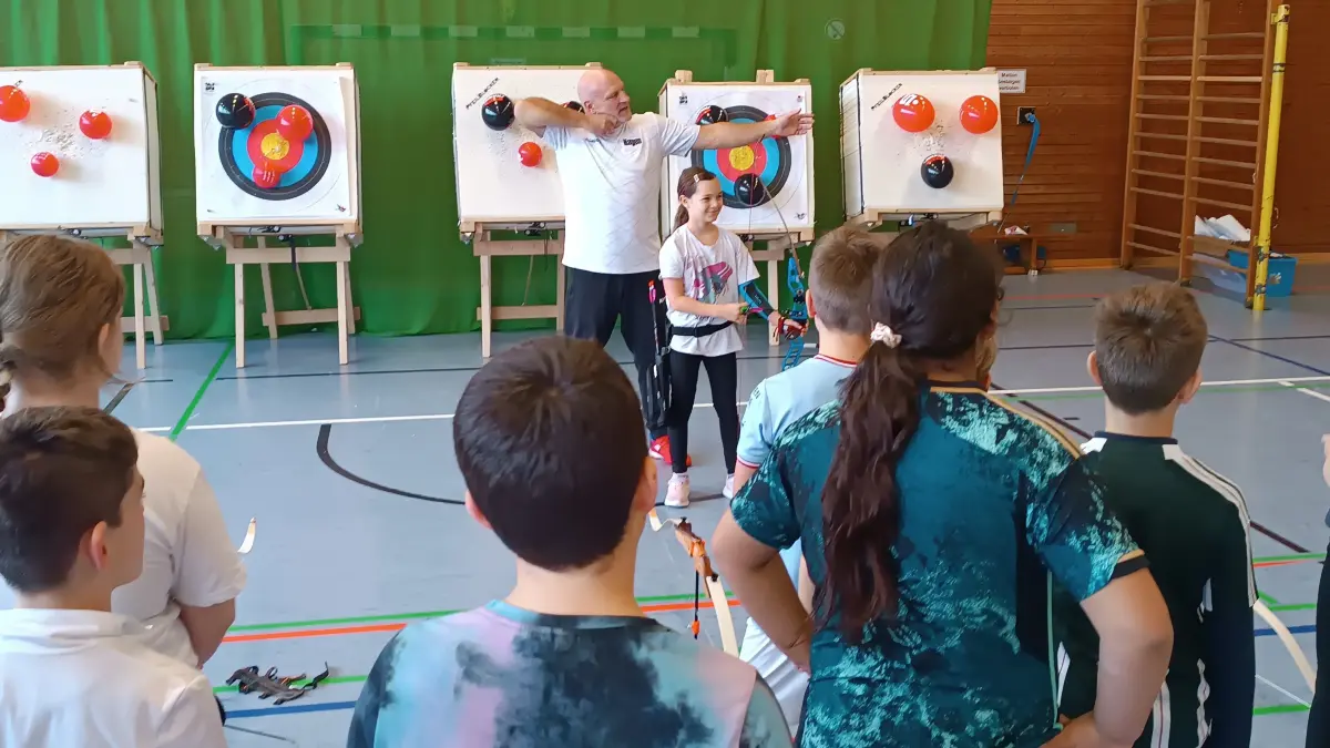 Kreismeisterin Amy Stiegler und Hagen Gräter vom Schützenverein Jungingen zeigen den Schülerinnen und Schüler, wie man den Bogen hält.