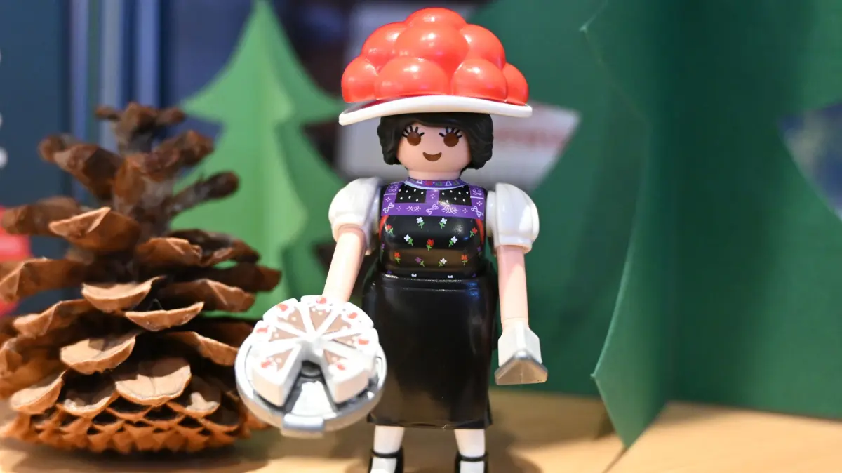 Sammelkarten, Lego, Plueschtiere: Spielzeugfirmen entdecken Erwachsene: Playmobilfigur "Schwarzwald Marie" im Regal der Touristinfo Ettlingen (Foto vom 15.12.2025). Die 77.000 Exemplare der im Herbst aufgelegten, limitierten Figur mit rotem Bollenhut und der beruehmten Schwarzwaelder Kirschtorte waren sofort ausverkauft. Spieltrieb, Nostalgie oder Lifestyle-Trend: Als Kidults werden Erwachsene bezeichnet, die sich gerne mal teure Lego-Sets und seltene Comics goennen oder Plueschfiguren sammeln. Fuer Spielwarenhersteller rueckt diese Zielgruppe zunehmend in den Fokus. (Siehe epd-Feature vom 18.12.2025)