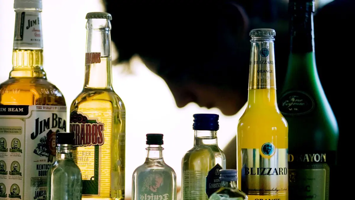 Jugendliche und Alkohol: ILLUSTRATION - 07.09.2009, Mecklenburg-Vorpommern, Schwerin: ARCHIV - Ein Jugendlicher sitzt hinter Flaschen mit Alkohol. In Mecklenburg-Vorpommern sind im vierten Jahr in Folge mehr Jugendliche mit einer Alkoholvergiftung ins Krankenhaus gekommen. (zu dpa: «Weniger jugendliche Komatrinker in Hessens Kliniken») Foto: Jens Büttner/dpa-Zentralbild/dpa +++ dpa-Bildfunk +++