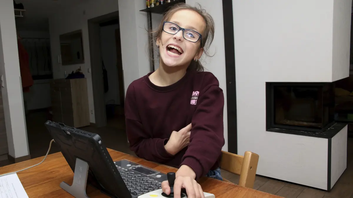 Lilly Warth in ihrem Gehwagen (einmal mit Papa Markus Warth) sowie an ihrem Laptop.