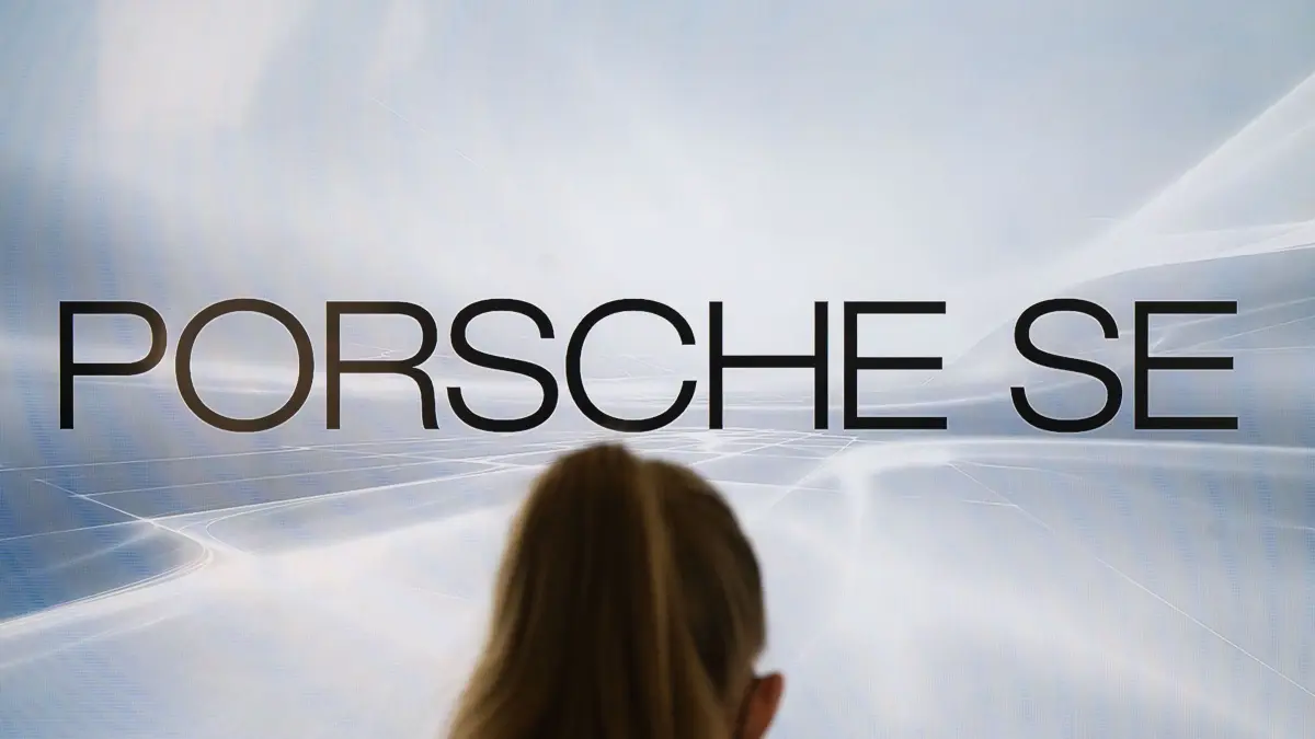 ARCHIV - 29.03.2022, Baden-Württemberg, Stuttgart: Eine Frau steht vor einem Monitor mit dem Logo der Porsche SE (gestellte Szene). (zu dpa: «VW-Dachgesellschaft kämpft mit Schwäche der Beteiligungen») Foto: Marijan Murat/dpa +++ dpa-Bildfunk +++