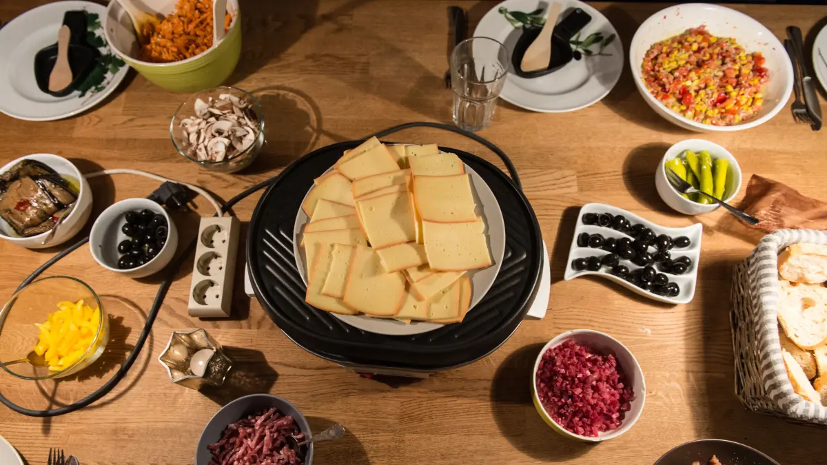 ARCHIV - Raclettekäse und Schalen mit Zutaten stehen am 31.12.2014 in Freiburg (Baden-Württemberg) auf einem Tisch. (zu dpa "Essensverschwendung an Weihnachten: «Niemand soll zu kurz kommen»" vom 21.12.2015) Foto: Patrick Seeger/dpa +++ dpa-Bildfunk +++
