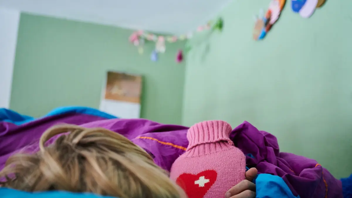 Krankes Kind (Symbolbild): ILLUSTRATION - 11.09.2021, Berlin: Ein Kind liegt mit einer Wärmflasche im Bett im Kinderzimmer. Elternpaare können laut AOK Plus auch 2026 je gesetzlich versichertem Kind für 15 Arbeitstage Kinderkrankengeld beantragen. (zu dpa: «AOK Plus: 76 Millionen für Eltern mit kranken Kindern») Foto: Annette Riedl/dpa +++ dpa-Bildfunk +++