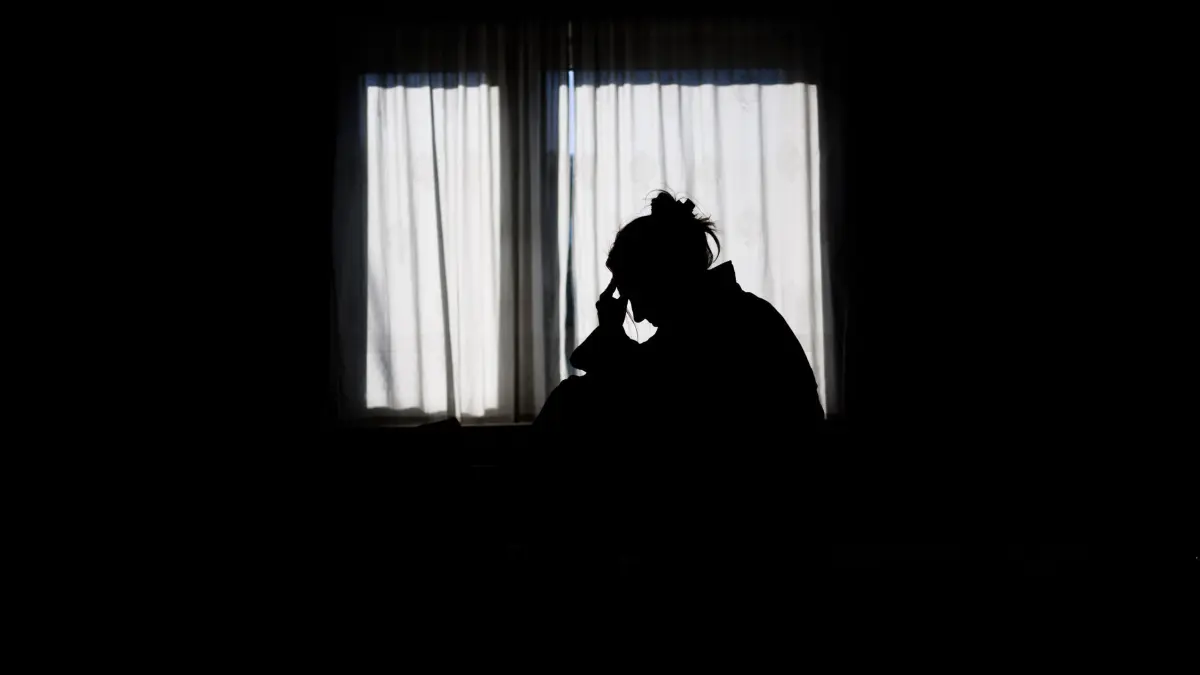 Symbolbild Einsamkeit: ARCHIV - 19.02.2025, Niedersachsen, Hannover: ILLUSTRATION - Die Silhouette einer Frau zeichnet sich vor einer hellen Fensterfront ab (gestellte Szene). (zu dpa: «Einsamkeit, Angst - viele suchen Halt bei Telefonseelsorge») Foto: Julian Stratenschulte/dpa +++ dpa-Bildfunk +++